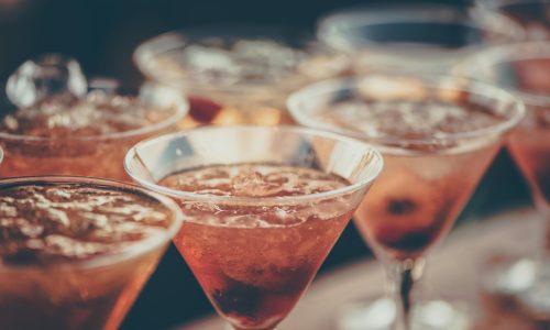 a row of cocktails with ice in a martini style glass